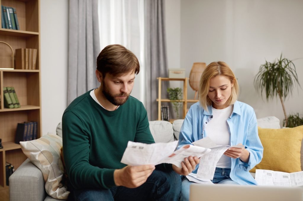 Serious Couple Paying Bills. Worried Couple Calculating And Paying Bills